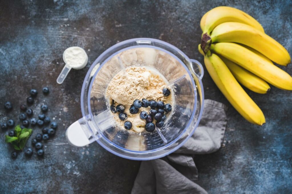 W blenderze znajdują się banany, borówki i odzywka proteinowa