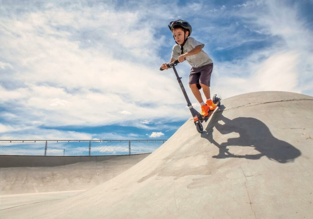 Chłopiec jeździ na hulajnodze w skateparku