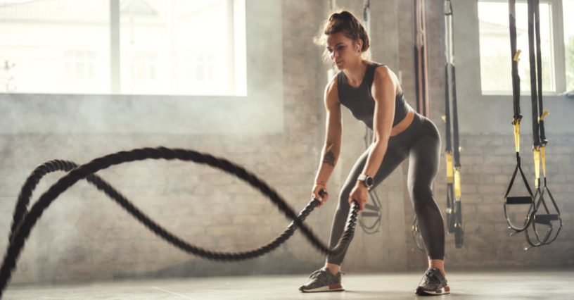 Kobieta w odzieży sportowej trenuje z linami battle rope
