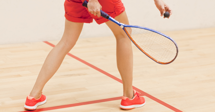 Mężczyzna gra w squasha na drewnianym korcie