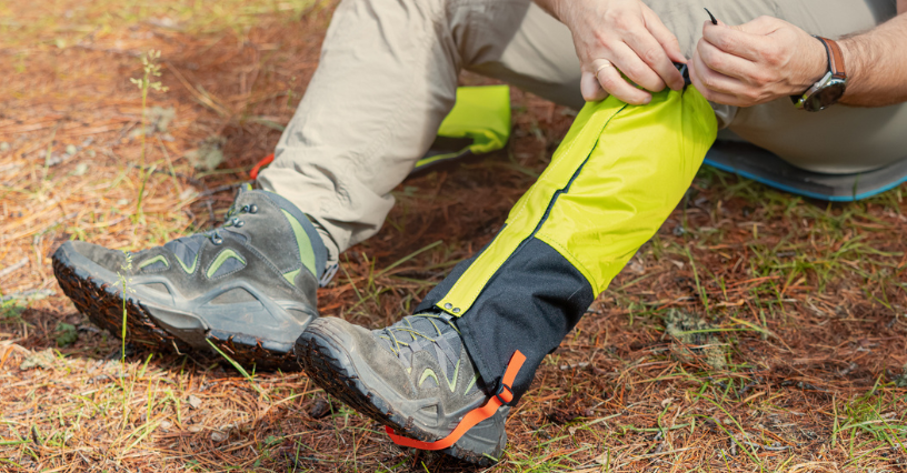 Osoba zakłada ochraniacze na buty, przygotowując się do trekkingu