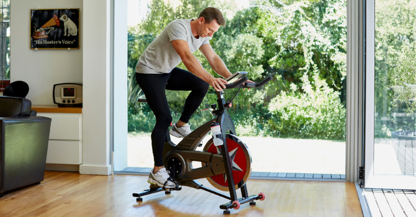 Mężczyzna ćwiczy na rowerku spinningowym w domu