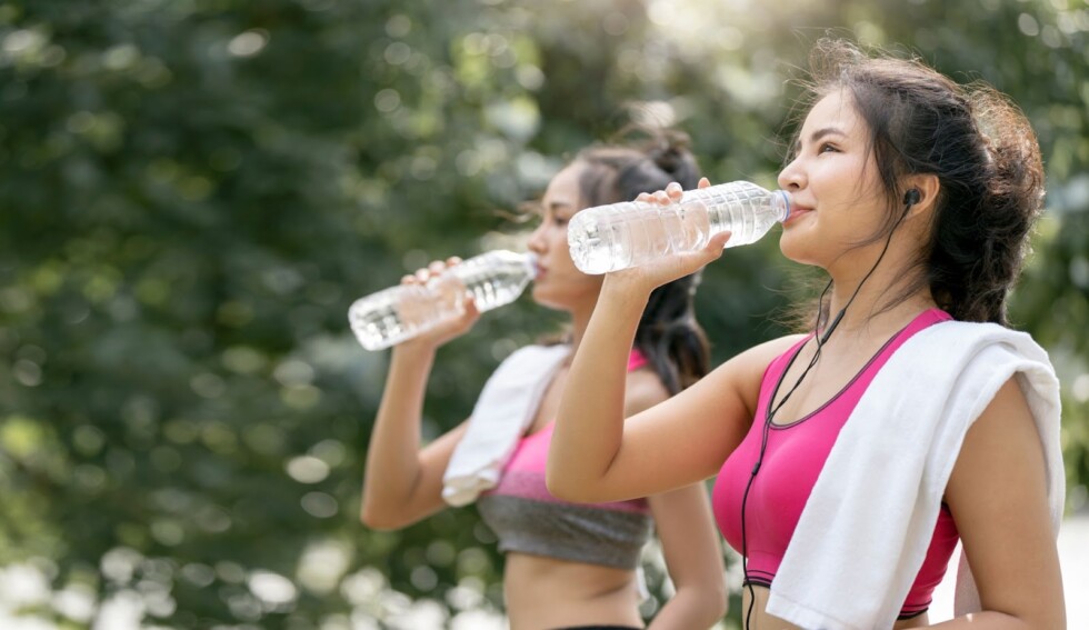 Kobiety w sportowych strojach piją wodę podczas przerwy w treningu na świeżym powietrzu