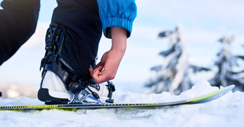 Narciarz zapina buty snowboardowe na ośnieżonym stoku