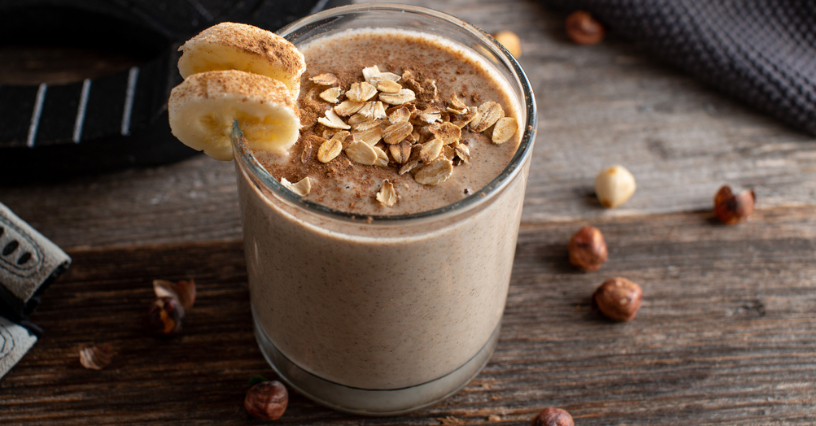 Szklanka smoothie bananowego z płatkami owsianymi na drewnianym stole