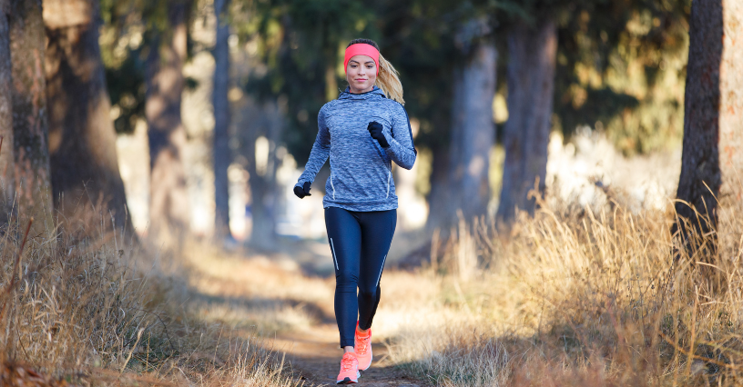 Kobieta w sportowym stroju biegnie leśną ścieżką