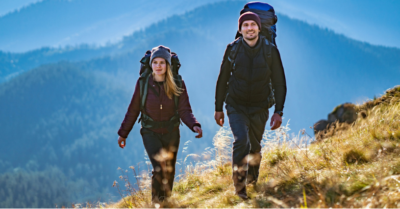Dwoje ludzi wędruje z plecakami trekkingowymi po górskim szlaku 
