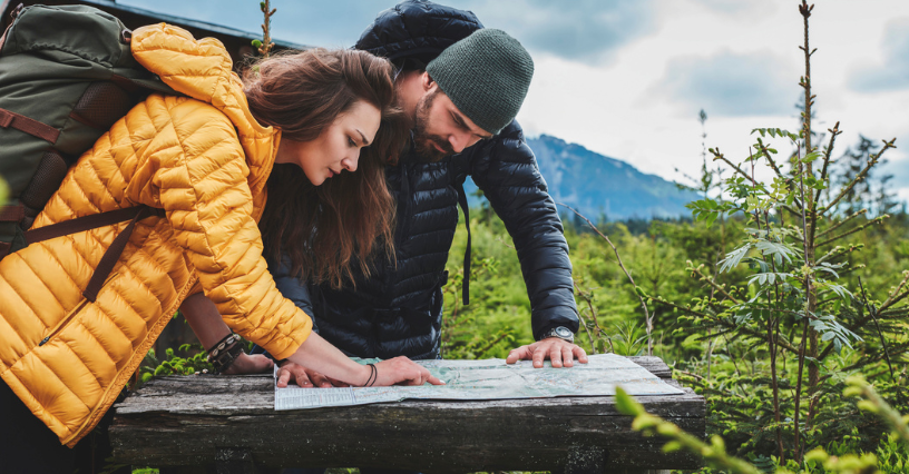 Para w odzieży outdoorowej studiuje mapę na łonie natury 