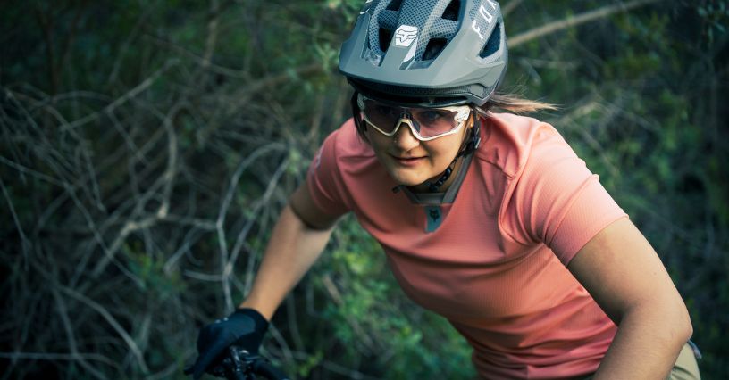 Kobieta w koszulce rowerowej i kasku jadąca na rowerze MTB