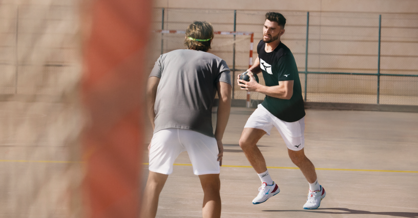 Mężczyzna w odzieży sportowej z piłką do piłki ręcznej zmierzający w stronę bramki