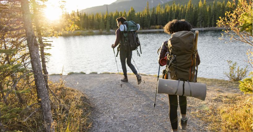Kobieta i mężczyzna z plecakami trekkingowymi wędrujący ścieżką przy rzece