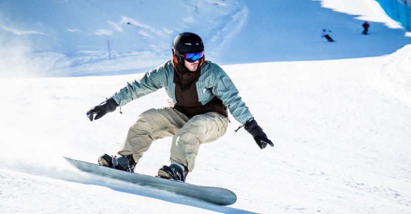 Mężczyzna zjeżdżający po stoku na desce snowboardowej