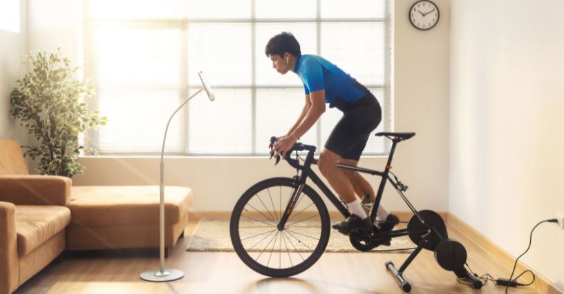 Mężczyzna trenujący z aplikacją rowerową na trenażerze rowerowym w domu