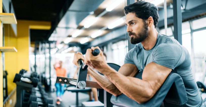 Mężczyzna ćwiczący biceps na maszynie z modlitewnikiem