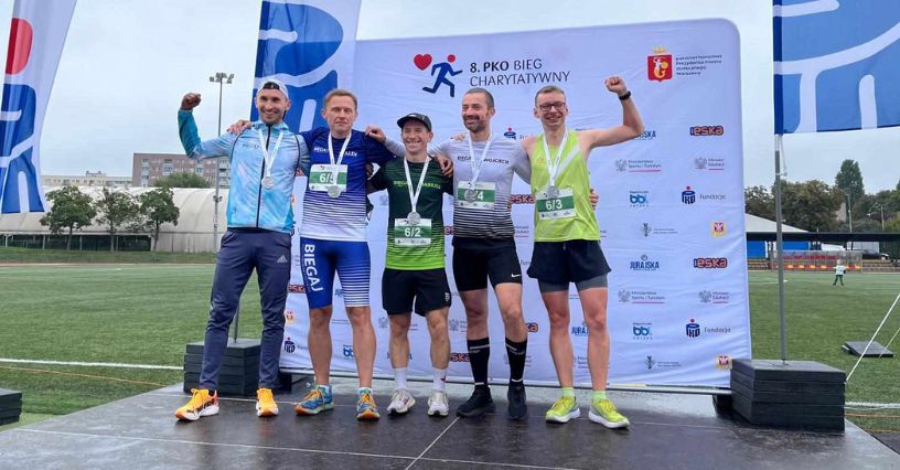 5 mężczyzn cieszących się medalami za ukończenie biegu 