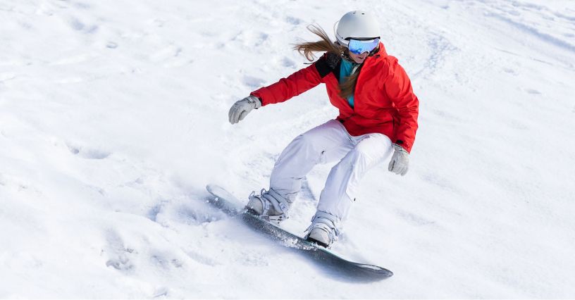 Kobieta zjeżdżająca na desce snowboardowej