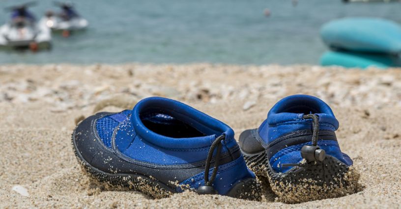 Dziecięce buty do wody z neoprenu leżące na piasku nad morzem