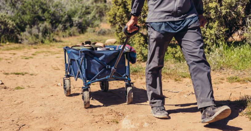 Mężczyzna ciągnący wózek transportowy składany Gregory  Alpaca Gear Wagon
