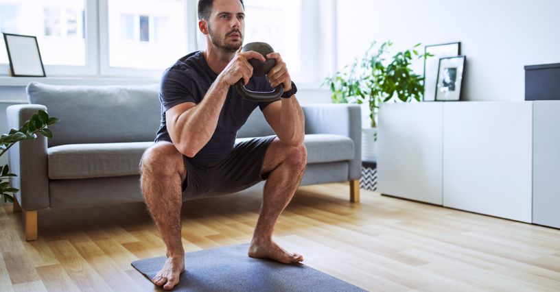 Mężczyzna wykonujący przysiad z kettlebell w domu