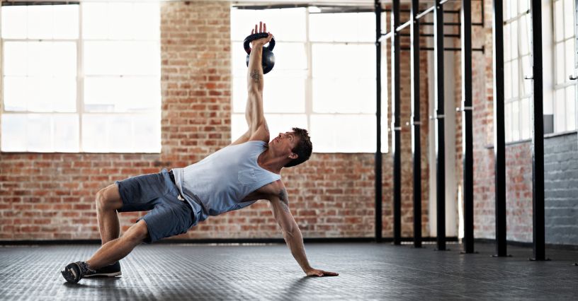 Mężczyzna wykonuje tureckie wstawanie z kettlebell na siłowni 